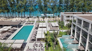 A resort with multiple swimming pools, sun loungers, and a beach view.