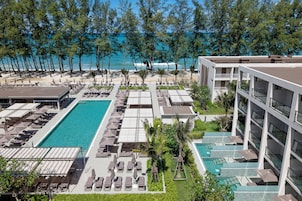 Un resort con varias piscinas, tumbonas y vista al mar.
