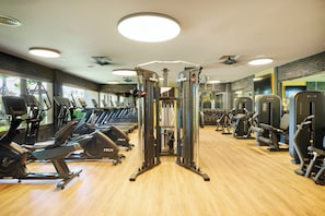Un gimnasio con diversos equipos de ejercicio, como cintas de correr, bicicletas estáticas y máquinas de pesas.