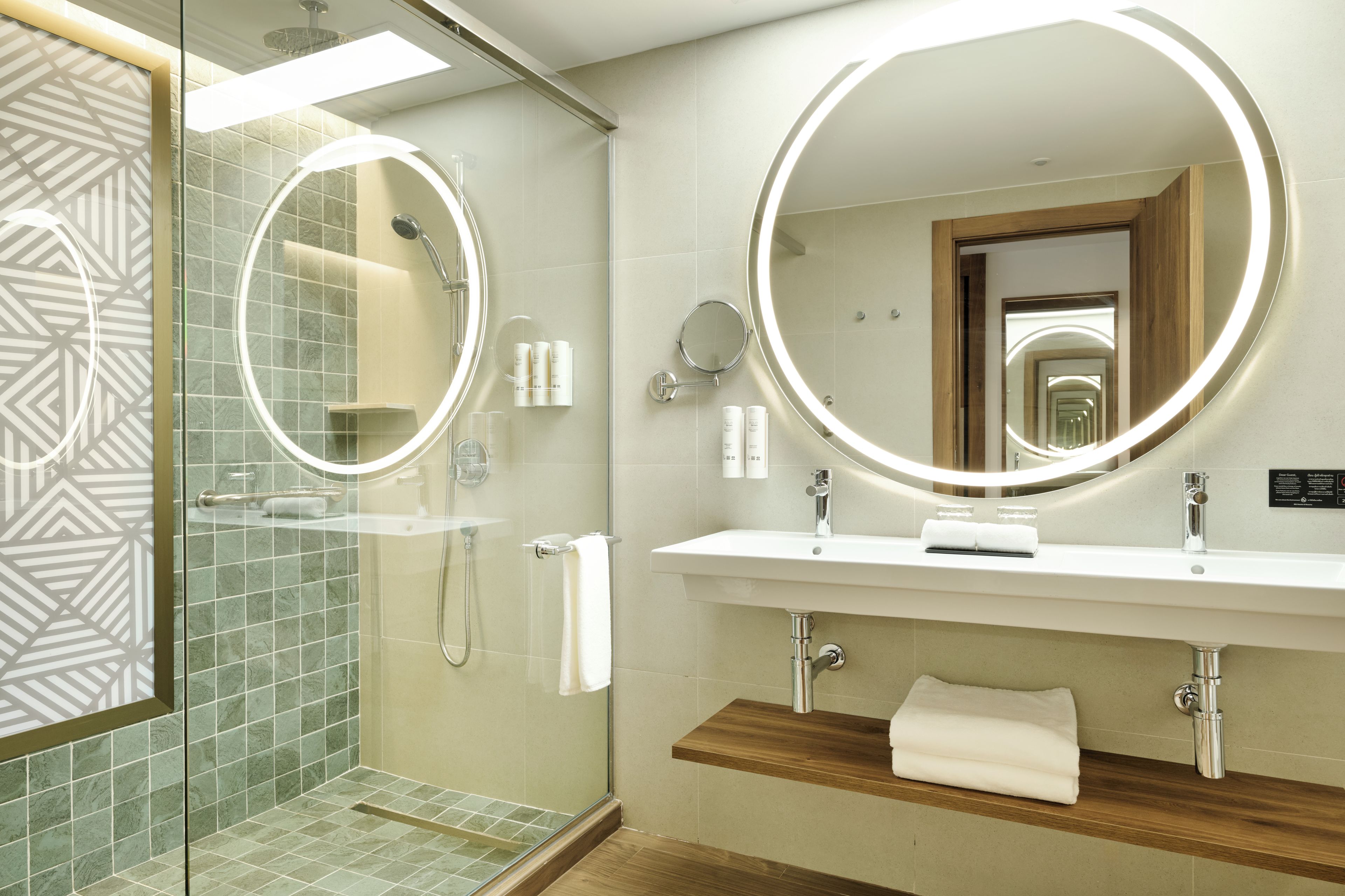Une salle de bain moderne avec une douche à parois de verre, un meuble-lavabo avec un miroir et une étagère en bois.