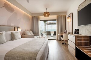 Una habitación de hotel con una cama grande, un escritorio y vistas a la playa.