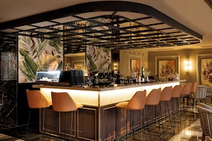 A bar area with a long counter, multiple stools, and a decorative ceiling. - Hotel Riu Palace Phuket - All Inclusive (Mai Khao)