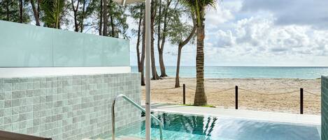 A poolside area with lounge chairs and a view of the beach.
