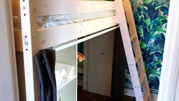 A bunk bed with a desk underneath, a small shelf, and a curtain.