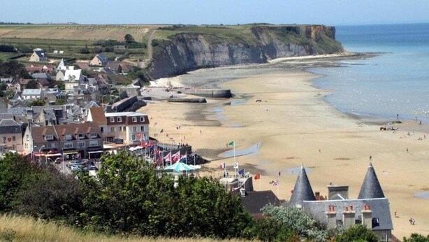 Een kustplaatsje met een zandstrand, gebouwen en kliffen.