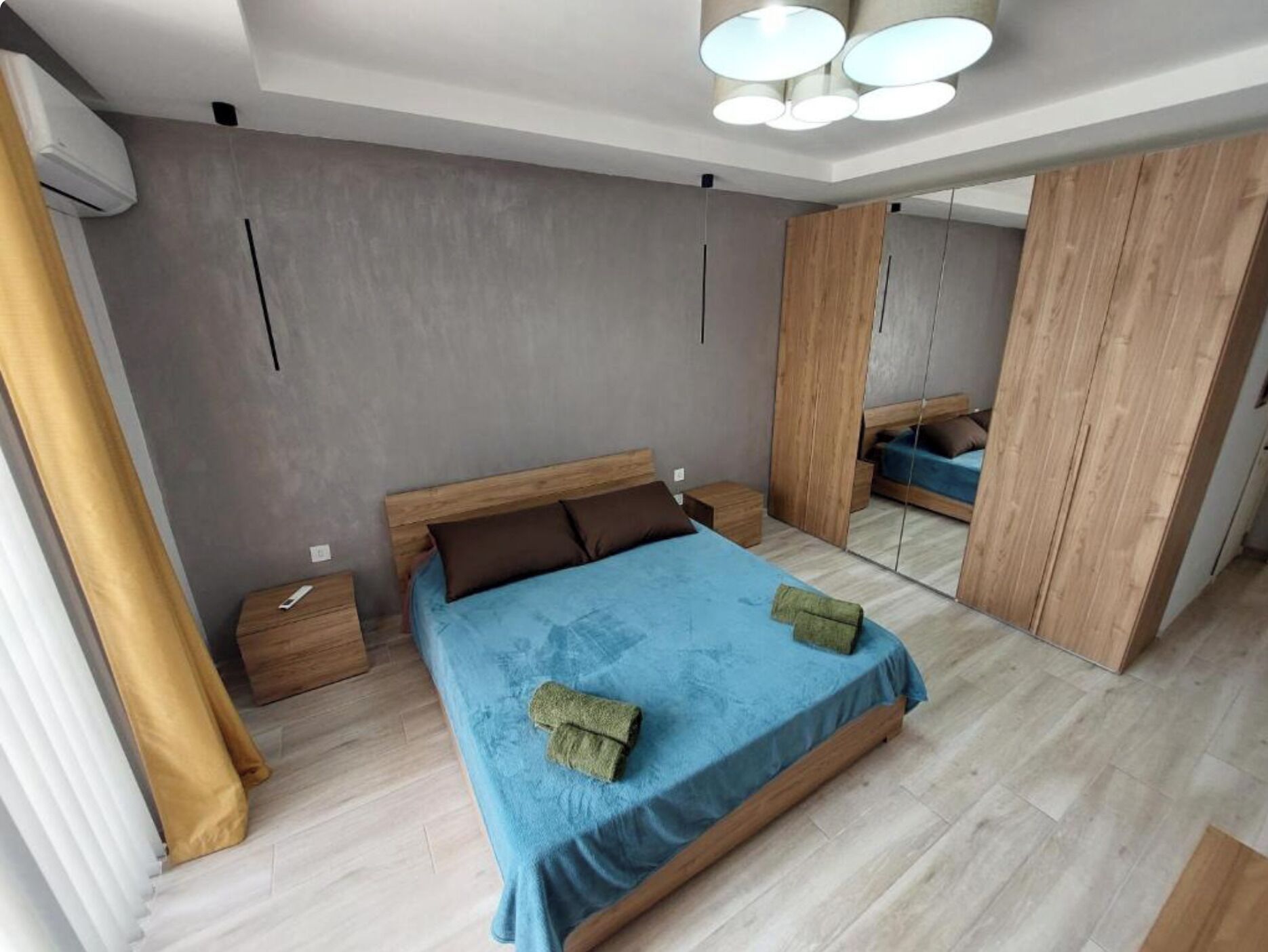 A modern bedroom with a bed, wooden wardrobe, and a mirror.