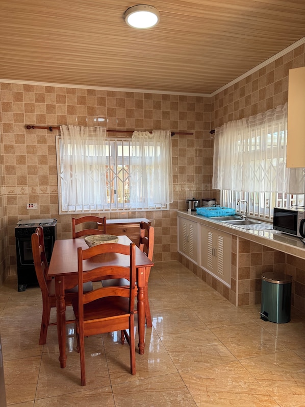 Une cuisine équipée d’une table à manger, de chaises, d’une cuisinière, d’un four à micro-ondes et d’un évier.
