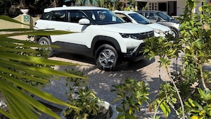 A white SUV parked in a driveway with a house in the background.