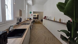A modern kitchen with a wooden countertop, a sink, and a dining area in the background. - Ganaceto100   Blu apartment   MW Collection (Modena)