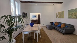 A modern living room with a wooden dining table, a grey sofa, and a large plant. - Ganaceto100   Blu apartment   MW Collection (Modena)