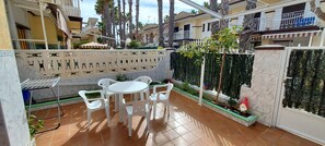 Eine Terrasse mit rundem Tisch und Stühlen, einem Grill und einer Zierwand.