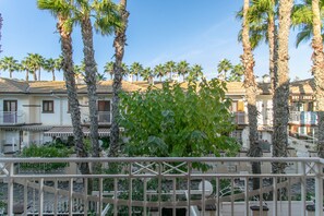 A hotel with multiple-story buildings, palm trees, and a balcony with a railing.