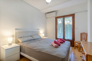Un dormitorio con cama, mesitas de noche, un escritorio y una silla.