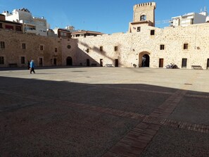 A courtyard with stone buildings, a tower, and a paved area. - Bungalow 'Iratxe En Santa Pola' with Private Terrace, Wi-Fi and Air Conditioning (Santa Pola)