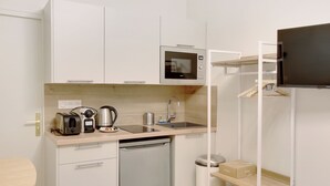 A compact kitchenette with a microwave, toaster, coffee maker, sink, and dishwasher. - Appartements rue Garnier (Neuilly-sur-Seine)