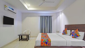 Une chambre d’hôtel équipée d’un lit, d’une chaise, d’une petite table, d’un téléviseur et d’un appareil de climatisation.