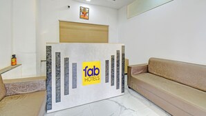 A reception desk with a 'fab hotels' logo, a sofa, and a small shelf with items. - Fabhotel Destination 41 (Pune)