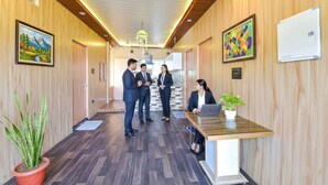 A reception area with wooden paneling, a reception desk, a potted plant, and framed artwork on the walls.
