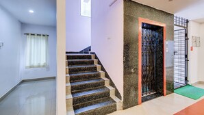 A staircase with a handrail, a door with a metal gate, and a green mat at the bottom. - Fabhotel Pushpa Grand (Hyderabad)