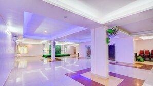 A spacious hotel lobby with a high ceiling, a green seating area, and a large decorative wall piece. - Fabhotel Pushpa Grand (Hyderabad)