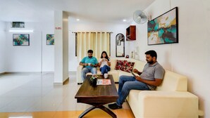 A modern living room with a sofa, a coffee table, and artwork on the walls. - Fabhotel Pushpa Grand (Hyderabad)