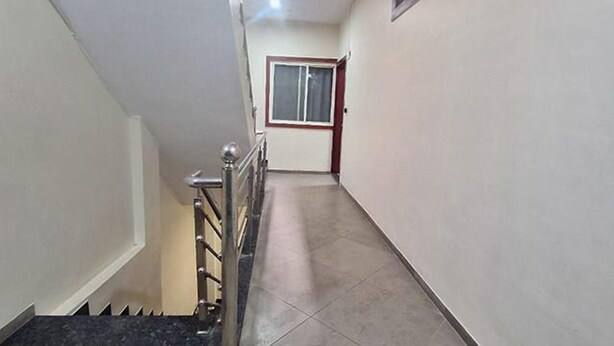 A narrow hallway with a staircase on the left, a door with a window at the end, and a tiled floor. - Fabhotel Ripon Palace (Ujjain)
