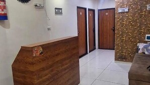 A reception area with a wooden reception desk, two wooden doors, and a tiled floor. - Fabhotel Ripon Palace (Ujjain)