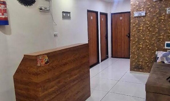 A reception area with a wooden reception desk, two wooden doors, and a tiled floor. - Fabhotel Ripon Palace (Ujjain)