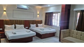 A hotel room with two beds, a sofa, and an air conditioning unit. - Fabhotel Ripon Palace (Ujjain)