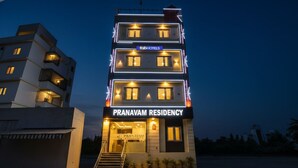 Un edificio de varios pisos con un letrero que dice 'Pranavam Residency' y 'Fab Hotels'.