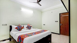 Een hotelkamer met een bed, een plafondventilator en een houten deur.