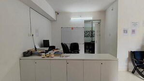 A small office with a white desk, black office chair, and a whiteboard. There are papers and a laptop on the desk. - Fabhotel Ekab Hospitality (Pune)