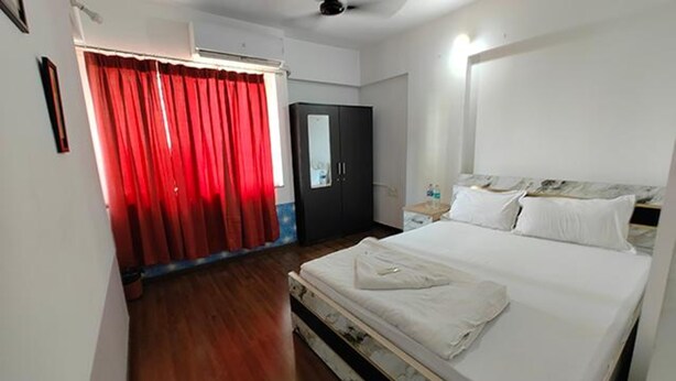 A hotel room with a bed, a wardrobe, a mirror, and a red curtain. - Fabhotel Ekab Hospitality (Pune)