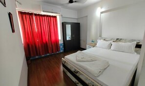 A hotel room with a bed, a wardrobe, a mirror, and a red curtain. - Fabhotel Ekab Hospitality (Pune)