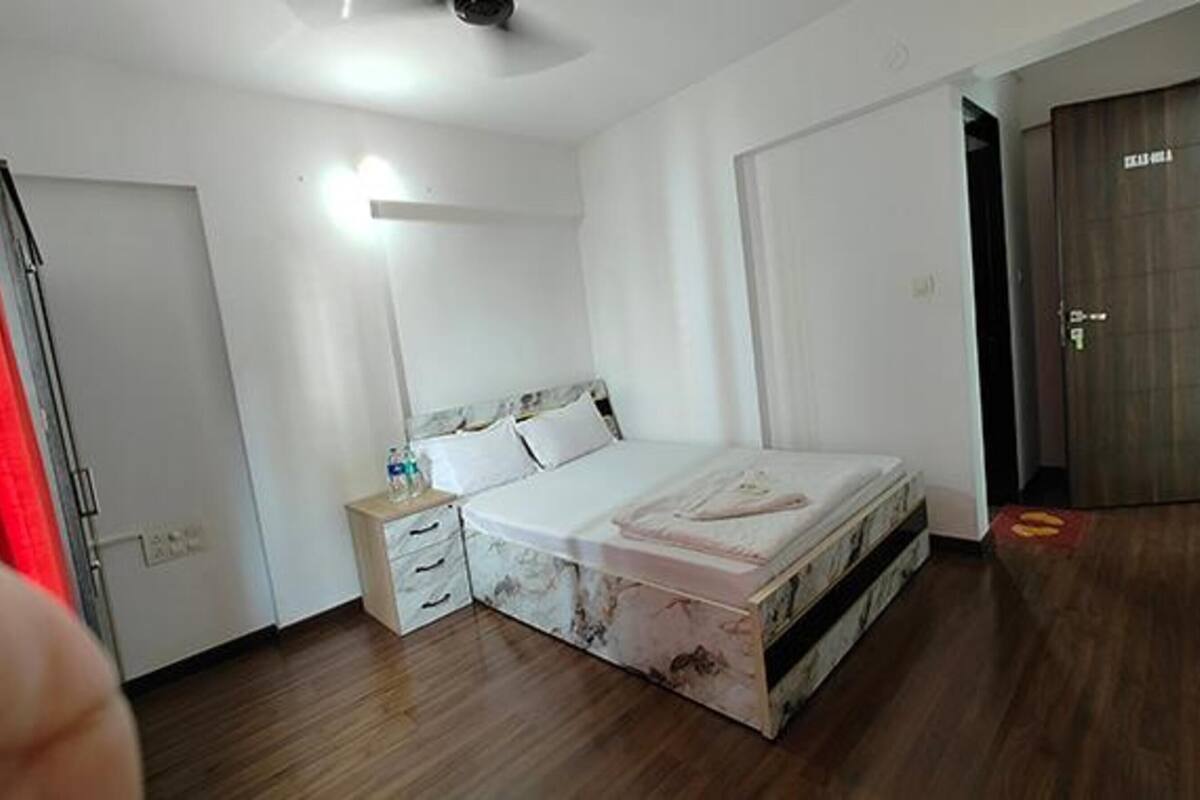 A bedroom with a bed, a nightstand, a mirror, and a door.