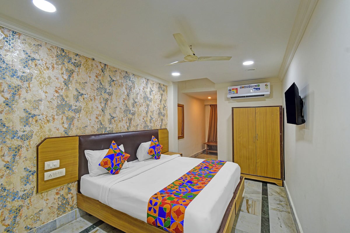 Habitación de hotel con cama, ventilador de techo, equipo de aire acondicionado y armario.