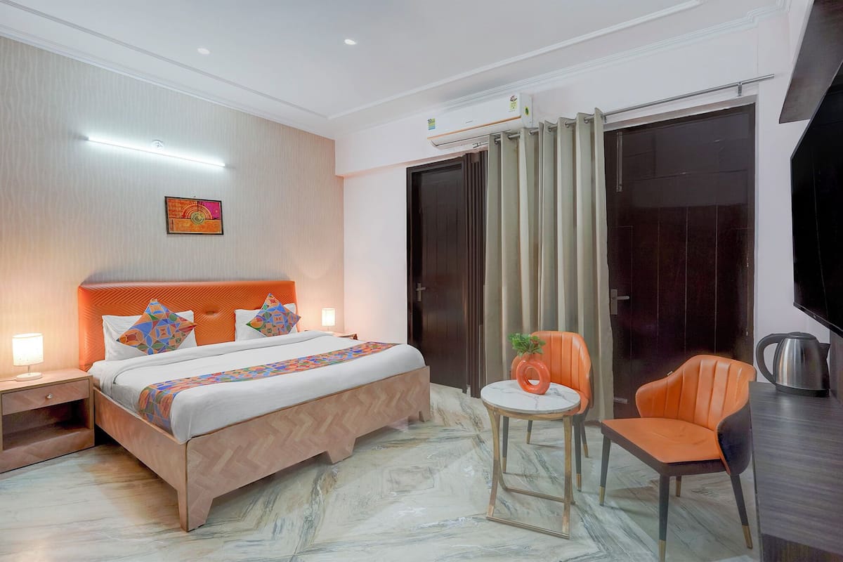 A hotel room with a bed, a desk, a chair, and a television.