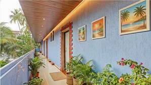 A corridor with a blue wall, wooden ceiling, and potted plants. - Fabhotel 22 Square Living Spaces (Calangute)