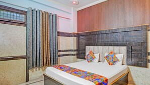 A bedroom with a bed, curtains, and a headboard. - Fabhotel Radha Palace (Vrindavan)