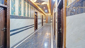 A hallway with marble floors and walls, featuring a series of doors and a ceiling with recessed lighting. - Fabhotel Radha Palace (Vrindavan)
