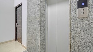 An elevator with a control panel displaying a blue light and a door with a metal handle. - Fabhotel Aakarshan Residency (New Delhi)