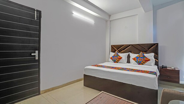 A bedroom with a bed, a wooden door, a nightstand, and a mirror. - Fabhotel Aakarshan Residency (New Delhi)