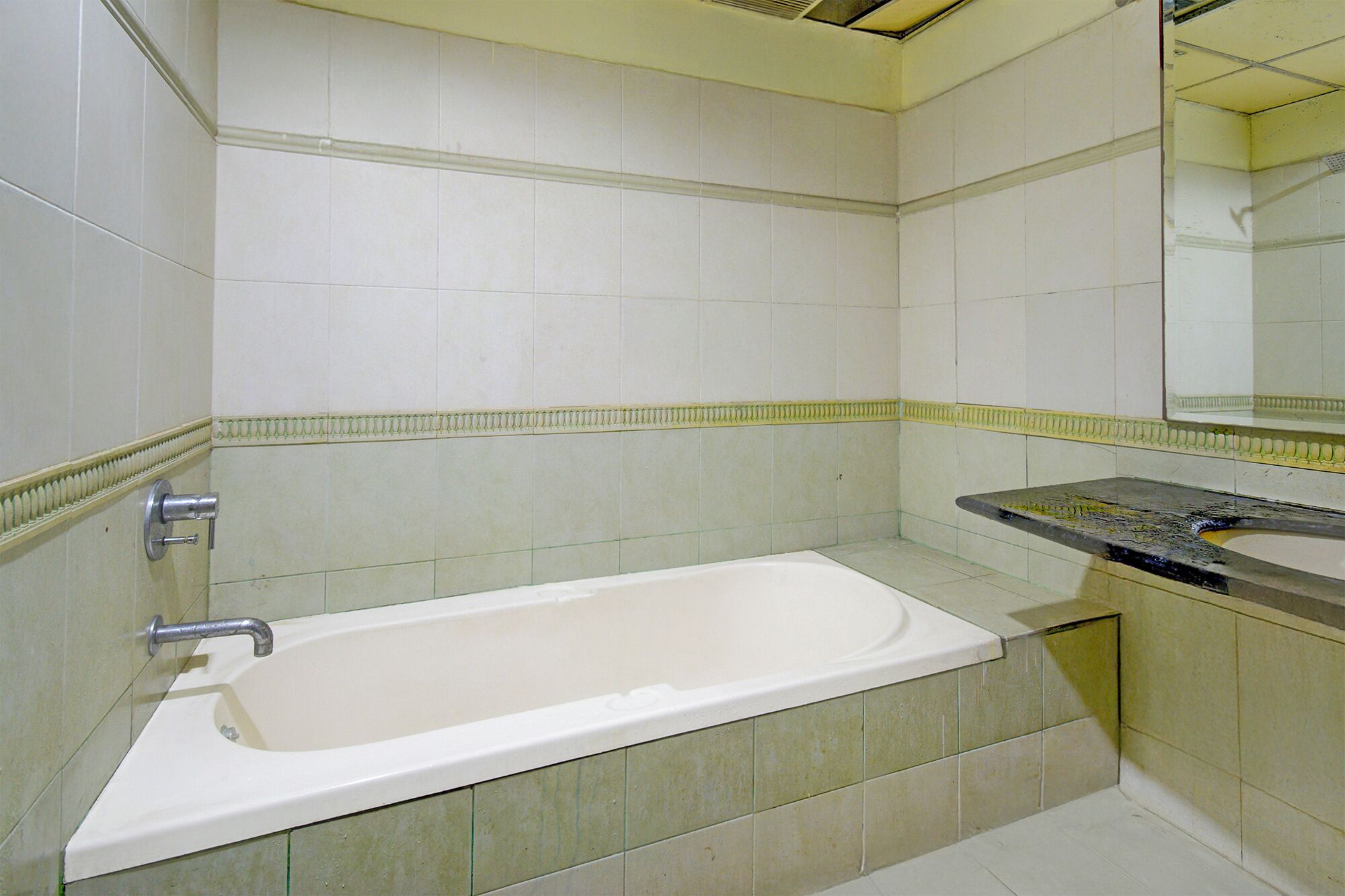A bathroom with a bathtub, a sink, and a mirror.