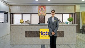 A hotel reception desk with a logo, a nameplate, and a decorative painting. - Fabhotel Ranjit Residency (Hyderabad)