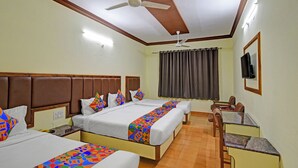 A hotel room with two beds, a desk, a chair, a television, and a ceiling fan. - Fabhotel Ranjit Residency (Hyderabad)