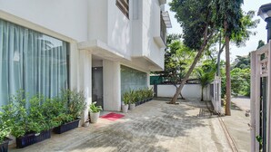 A clean, modern building with a concrete courtyard, potted plants, and a red mat. - Fabhotel Ans Kp Annex (Pune)