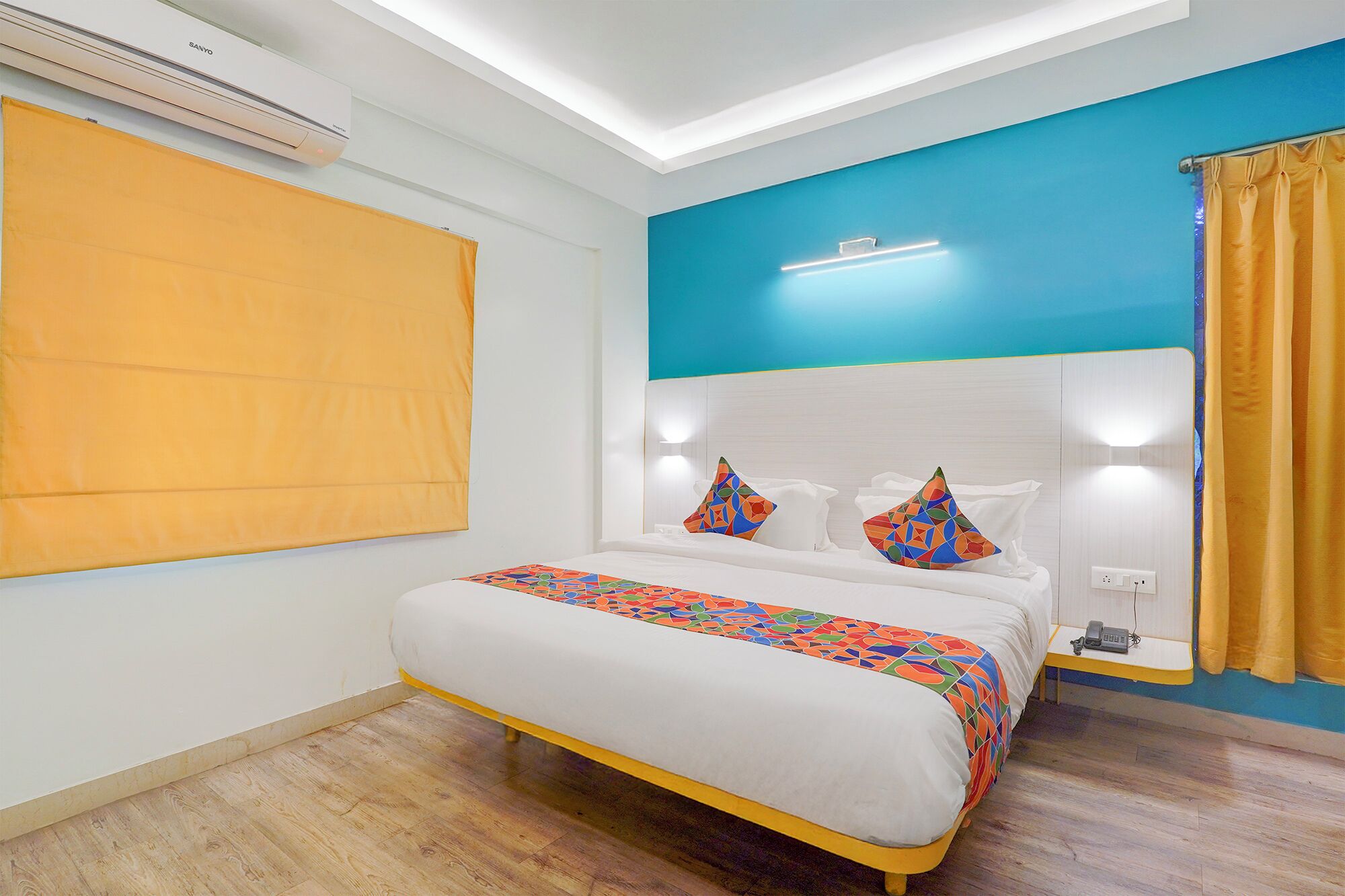 A hotel room with a bed, a nightstand, a telephone, and a wall-mounted air conditioner.