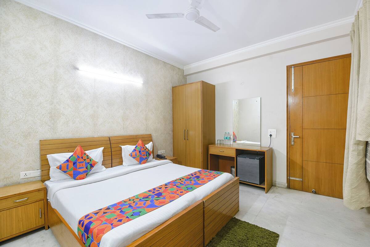 A hotel room with a wooden bed, a wardrobe, a desk, and a mirror.