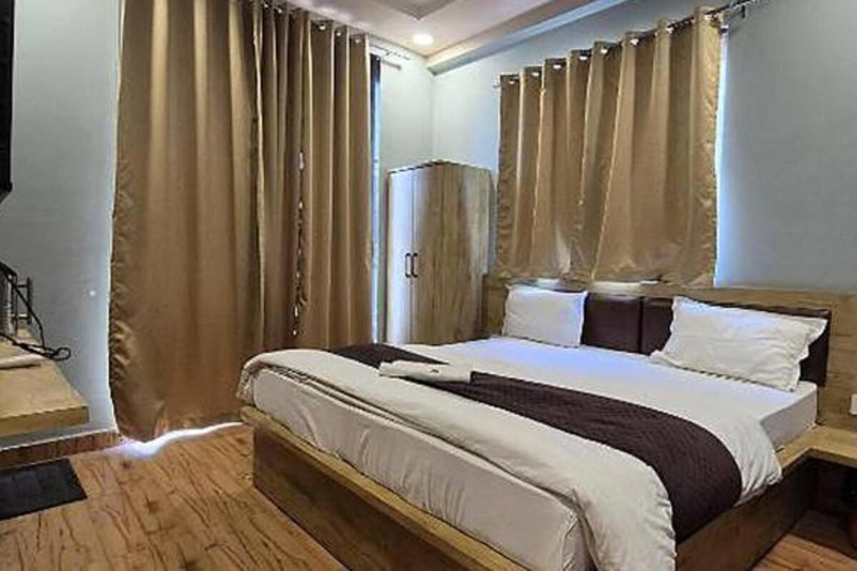 A bedroom with a wooden bed, beige curtains, and a wooden wardrobe.