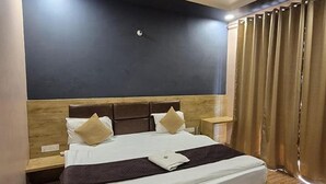 Ett hotellrum med en stor säng, ett träbeklätt sänggavel, två sängbord och ett fönster med gardiner.